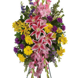 Standing floral spray with pink lilies, yellow daisies, and purple accents