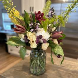 Mixed bouquet in a glass vase with lilies, orchids, and pale blooms