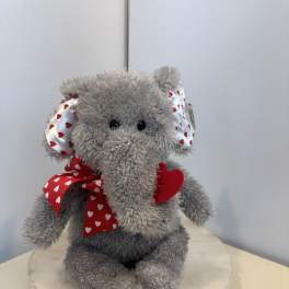 Gray plush elephant with red heart ribbon on a round base