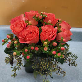Pink roses arranged in a low vase with berry-like accents