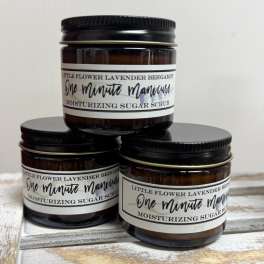Three amber jars of lavender bergamot sugar scrub stacked on a wooden surface.