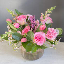 Pink roses and tulips arranged in a ribbed glass vase