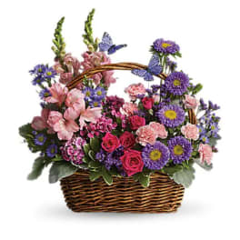 Basket arrangement of pink and purple flowers with butterfly accents