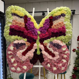 Large butterfly-shaped floral standing display in pink, purple, yellow, and green.