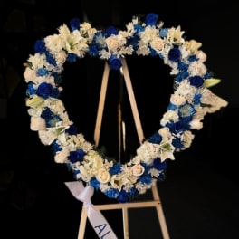 Heart-shaped floral wreath with blue and white flowers on an easel