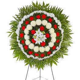 Circular funeral wreath with red and white flowers on a stand