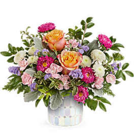 Mixed bouquet of pink, peach, white, and purple flowers in a patterned vase