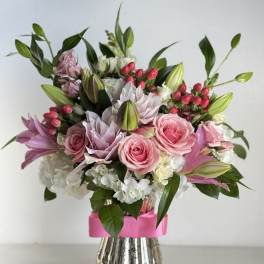 Pink roses and lilies in a silver vase with a pink ribbon