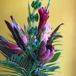Tropical floral arrangement with pink protea and tall green spikes
