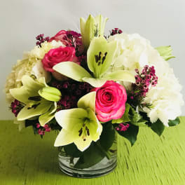 Bouquet of pink roses, white lilies, and white hydrangeas in a glass vase