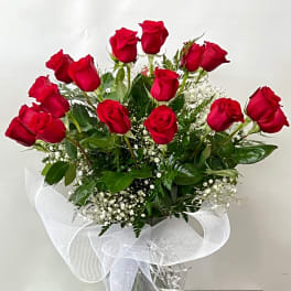 Bouquet of red roses in a clear vase with white ribbon