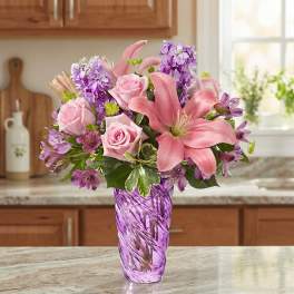 Pink lilies and roses in a purple glass vase