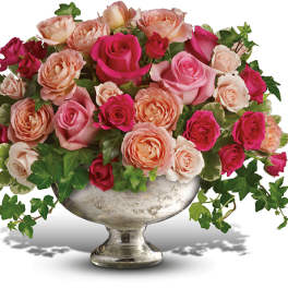 Pink and peach roses arranged in a silver pedestal vase