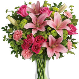 Pink lilies and roses arranged in a clear glass vase