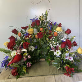 Large mixed floral arrangement with red and yellow roses and lilies
