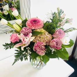 Mixed pink and white flower arrangement with roses, lilies, tulips, and hydrangea in a clear glass vase