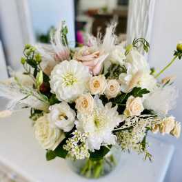 Round glass vase of white and blush flowers in a soft, airy arrangement