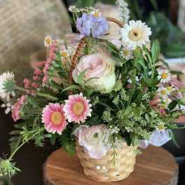 Basket arrangement of pink and white flowers with daisies and roses