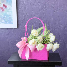 White tulips in a bright pink gift basket with a ribbon