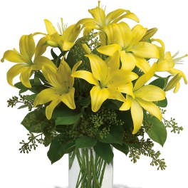 Yellow lilies arranged in a clear glass vase