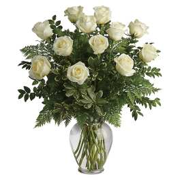 White roses in a clear glass vase with mixed greenery
