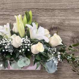 White roses and lilies in a low rectangular vase arrangement