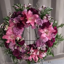 Pink and purple floral wreath on a black stand