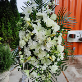 White funeral spray with lilies, roses, and chrysanthemums on a stand