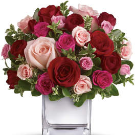 Bouquet of red, pink, and blush roses in a clear glass vase