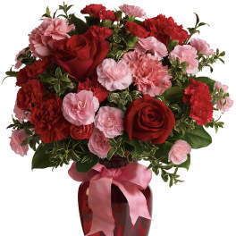 Red roses and pink carnations in a red vase with a pink ribbon