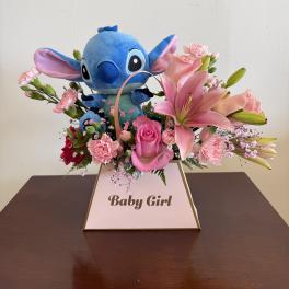 Pink lily and rose arrangement with blue plush toy in a Baby Girl box.