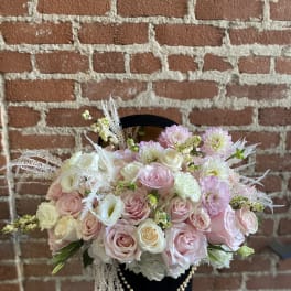 Pink and white rose bouquet in a black hatbox with pearl strands