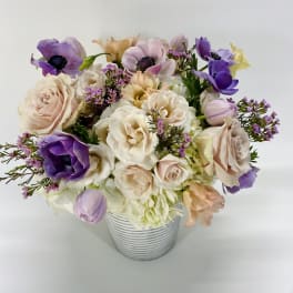 Pastel bouquet of roses and purple anemones in a striped vase