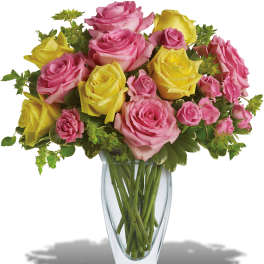 Pink and yellow roses arranged in a clear glass vase