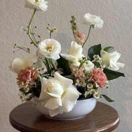 White roses and pink carnations in a white bowl vase