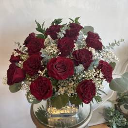 Bouquet of deep red roses with white filler flowers in a glass vase