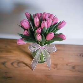 Pink tulips in a clear glass vase with a sheer ribbon