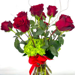 Red roses arranged in a clear glass vase with a red ribbon