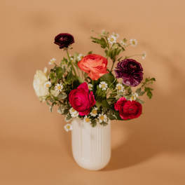 Mixed bouquet of ranunculus and daisies in a white vase