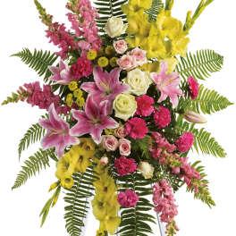 Standing floral spray with pink lilies, roses, and yellow gladiolus on an easel