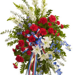 Standing floral spray with red carnations, white lilies, and blue flowers