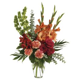 Tall bouquet of orange gladiolus, red roses, and carnations in a clear vase