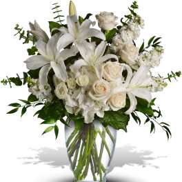 White lilies and roses arranged in a clear glass vase