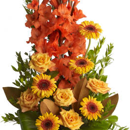 Orange gladiolus and yellow roses with gerbera daisies in a brown vase