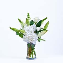 White flowers and lily buds arranged in a clear glass vase