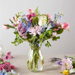 Mixed bouquet of pastel flowers in a clear glass vase