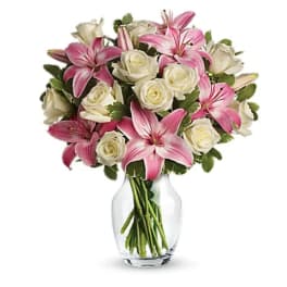 Pink lilies and white roses arranged in a clear glass vase