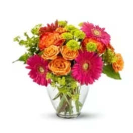 Bright mixed bouquet of gerbera daisies and roses in a clear glass vase