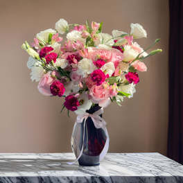 Pink and white mixed bouquet in a dark glass vase with a ribbon