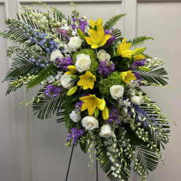 Large standing floral spray with yellow lilies, white roses, and purple flowers